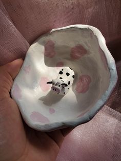 a hand holding a small ceramic dalmatian in a bowl