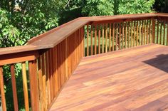 a wooden deck with railings and trees in the background