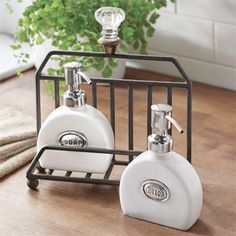 two white soap dispensers sitting on top of a wooden table next to a potted plant