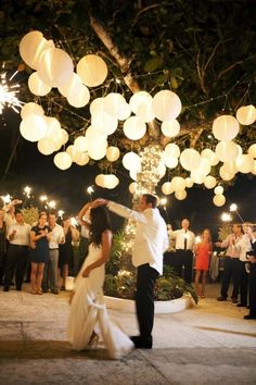 a bride and groom dancing under lanterns at their wedding