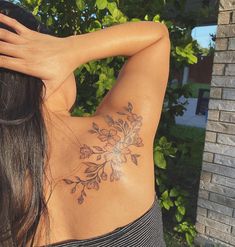 the back of a woman's shoulder with flowers tattooed on her left arm and chest