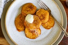 a plate topped with pancakes covered in butter next to a fork and glass of milk