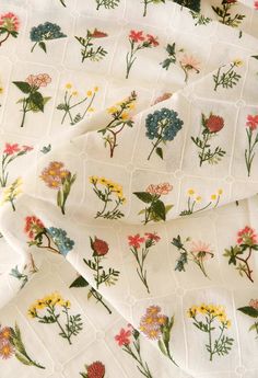 the fabric has flowers on it and is white with yellow, red, blue and green