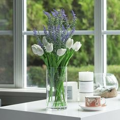 a vase filled with flowers sitting on top of a white table next to a window