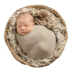 a newborn baby is curled up in a wicker basket on top of some wool