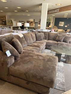 a living room filled with lots of couches and furniture in a store front window