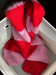 a red and pink scarf sitting in a white box