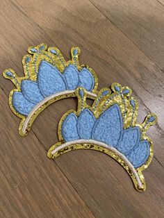 two blue and gold crowns sitting on top of a wooden floor