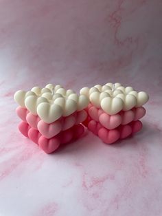 two pink and white heart shaped candles sitting on top of a table