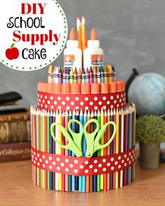 a cup filled with markers and scissors on top of a wooden table next to books