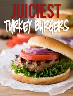 a burger with lettuce, tomato and onion on it sitting on wax paper