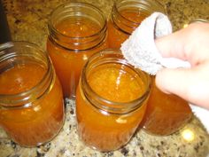 a person wiping off some jars with a cloth on top of the jars in front of them