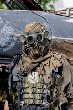 a man with goggles and a mask on standing in front of an old truck