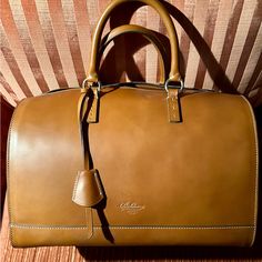 Nwt - Never Used - Boldrini Selleria Satchel Handbag. The Bag Measures 13” L X 10” H X 8 1/2” D. It Is Made Of Vacchetta / Calfskin Leather In Beautiful, Rich Camel Color. There Are Leather Side Gussets With A Full Two-Ended Zipper Opening At Either End. Gold Tone Hardware. This Is A Arm / Handbag. No Shoulder Strap. **Please Note** The Bag Has Two Minor Scratches Near Id Tag - Please See Photo. Possibly Occurred During Shipment - Does Not Detract From The Handbag. The Interior Has A 100% Red Co Brown Briefcase With Top Handle And Dust Bag, Top Handle Brown Travel Bag With Dust Bag, Timeless Brown Bags For Everyday Luxury, Classic Everyday Luxury Tote Bag, Classic Brown Satchel For Everyday Luxury, Brown Timeless Bag For Everyday Luxury, Classic Everyday Luxury Shoulder Bag With Leather Handles, Classic Business Travel Bag With Dust Bag Included, Classic Business Travel Bag With Dust Bag