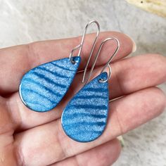 a person is holding two blue earrings in their hand