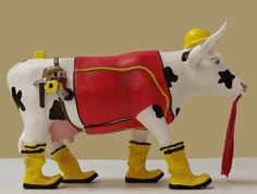 a toy cow is wearing yellow boots and a red dress with a hat on it's head