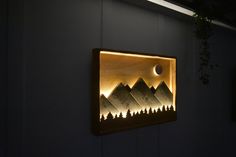 a wall mounted light with mountains and trees on it