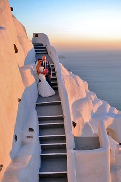 a bride and groom are sitting on the stairs to their wedding ceremony venue at sunset