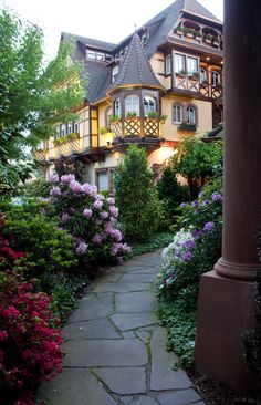 a large house with lots of flowers in the front yard and walkway leading up to it