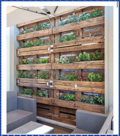 a wooden pallet filled with lots of plants on top of a wall next to wicker chairs