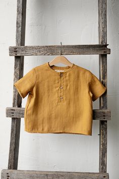 Short sleeve unisex shirt with three coconut buttons is made of 100% soft medium weight linen. The shirt is suitable for both girls and boys.  Details: - Choose size and embroidery in the drop down menu - Colour: Mustard - Composition: 100% Oeko-Tex certified linen - Three coconut buttons in the front - Medium weight linen - Unisex  - Relaxed silhouette - Linen care: machine wash gentle; tumble dry low, ironing optional - The price is for one shirt, other pictured items are not included Boys Linen Shirt, Shirt Linen, Linen Short, Cooking Apron, Linen Apron, Tee Dress, Dress Shirts, Linen Shirt, Unisex Shirt