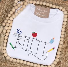 School days are cool days when you’re wearing a fun shirt like this! Each mini school supply item will be added around the name. No two shirts will look identical. When ordering an embroidered item, please specify your desired monogram initials or name, monogram font & thread color. All of the monogram options can be found here. Also, please note any additional special requests in the box provided. We will try our best to comply. Casual School Tops With Letter Embroidery, Casual Tops With Letter Embroidery For School, Casual Letter Embroidery Tops For School, School Spirit Tops With Letter Embroidery, Casual Tops With Embroidered Text For School, Casual Tops For Back To School Playtime, Casual Tops For Back To School, School T-shirt With Embroidered Text And Crew Neck, Cotton Tops For Playtime And Back To School