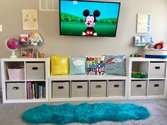 a child's bedroom with mickey mouse on the tv screen and storage bins