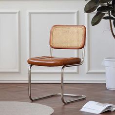 a brown chair sitting on top of a hard wood floor next to a potted plant