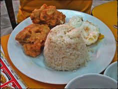 a plate with rice, fried eggs and other food on it sitting on a table