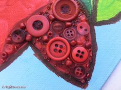 a close up of some buttons on a piece of art with colors and shapes in the background