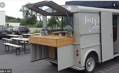 a food truck parked in front of a building with picnic tables and benches around it