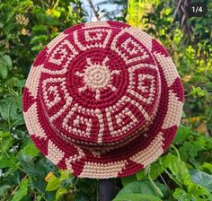 a red and white crocheted hat sitting on top of a pole