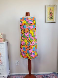 Adorable groovy 1960's dress! This is made from a cotton/rayon fabric in a bold colorful pattern with vines/roses/florals. Has a metal zipper up the front and pockets on both sides. Fully lined in pink. Label reads, "Pat Perkins" Very good vintage condition with minors signs of wash and wear in keeping with age. Shoulders have been taken in, could be let back out. This has been freshly cleaned and is ready to wear. Measurements Bust: Up to 44" Waist: 42" Hips: 42" Length: 39.5" Retro Multicolor Dress With Bold Print, Sleeveless Multicolor Mini Dress With Retro Print, Multicolor Mod Cotton Dresses, Mod Style Multicolor Floral Print Dress, Retro V-neck Dress With Vibrant Print, Multicolor Mod Dress With Floral Print, Multicolor Cotton Mod Dress, Mod Multicolor Floral Print Dress, Multicolor Mod Floral Print Dress