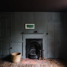 an empty room with a fire place in the corner and a basket on the floor