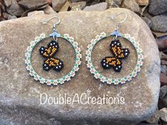 a pair of beaded hoops with a butterfly on them sitting on top of a rock