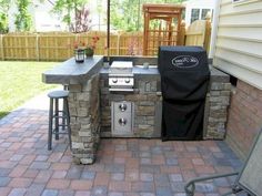 an outdoor grill with two stools next to it