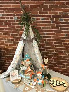 a table topped with cupcakes and cakes next to a teepee tent