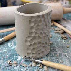 a clay cup sitting on top of a table next to some wood shavings