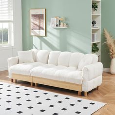 a white couch sitting on top of a hard wood floor next to a book shelf