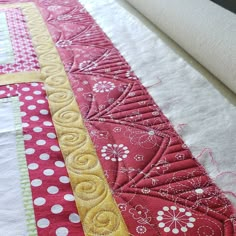 a red and yellow quilted table runner with white polka dots on the border,