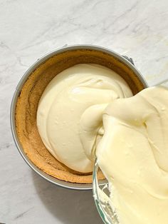 a cake in a pan being frosted with white icing on a marble counter top