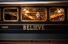 a woman wearing a hat looking out the window of a black and gold passenger train