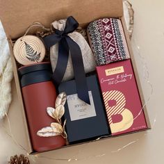 an open box filled with different types of items next to a pine cone and ribbon