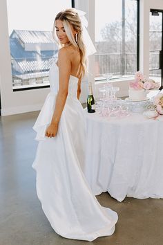 a woman in a wedding dress standing next to a table with a cake on it