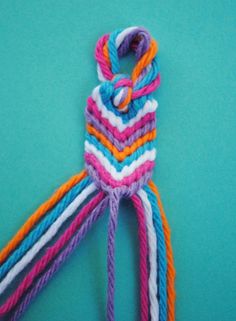 a multicolored piece of yarn on a blue background with one knot in the middle