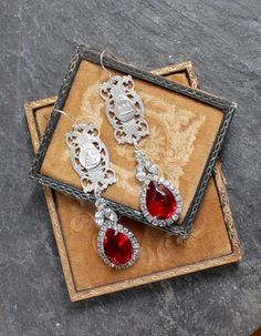 "The elaborate Paris components in these gorgeous earrings are salvaged from an antique France souvenir bracelet. The red and clear rhinestone drops are from a pair of mid 1900's earrings, and are a perfect complement to these lovely bracelet elements. The images on the bracelet links are the Opera House and the cathedral of the Sacred Heart of Montmartre. These are so beautiful with just about anything you would wear by they do make an elegant statement with a formal dress. They would also dres Red Metal Filigree Jewelry, Antique Silver Earrings With Vintage Charm, Vintage Crystal Drop Earrings For Jewelry Making, Ornate Red Drop Earrings, Victorian Jeweled Evening Jewelry, Vintage Metal Crystal Earrings For Wedding, Red Filigree Dangle Jewelry, Ornate Jeweled Jewelry For Evening, Vintage Ruby Evening Jewelry