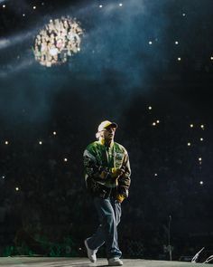 a man walking across a stage in front of a chandelier with lights on it