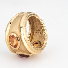 This is part of Chairish’s Fine Jewelry assortment.  Estate David Yurman Renaissance ring crafted in 18 karat yellow.    The out of production David Yurman ring is set with a center set Rhodolite garnet measuring 6mm. Two citrines measure 7mm x 5.5mm. The gemstones are in very good condition and free of cracks or chips. Weighing a hefty 16.6 grams the ring makes a great statement on the hand. The ring has a medium rise (6.5mm - 0.25 inches).  The ring is in very good condition and was recently l Luxury Yellow Sapphire Multi-stone Ring, Luxury Yellow Gold Ring Gemstone, Luxury Gold Amethyst Ring With Bezel Setting, Luxury Yellow Gold Amethyst Ring With Bezel Setting, Luxury Multi-stone Citrine Rings, Luxury Citrine Multi-stone Rings, Yellow Gold Rings With Bezel Setting And Wide Band, Classic Yellow Gold Topaz Ring With Multi-stone, Luxury Yellow Gold Topaz Ring With Bezel Setting