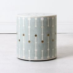 a white and blue stool with gold polka dots on it's sides, against a white wall