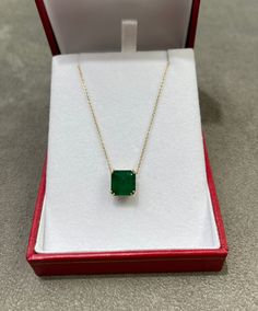 Featured here is a 4.18-carat stunning, Asscher cut emerald necklace in 14K yellow gold. Displayed in the center is a dark green emerald with very good eye clarity, accented by a simple double-prong gold mount, allowing for the emerald to be shown in full view. The earth mined emerald has a desirable lush green color with excellent qualities. An 18 inch is attached to the emerald pendant. This necklace is ideal for everyday use and is the perfect accessory for any outfit. Total Carat Weight: 4.1 Gift Emerald Necklace With Brilliant And Emerald Cuts, Brilliant Emerald Cut Gemstones For Gifts, Yellow Gold Cushion Cut Necklace As A Gift, Cushion Cut Yellow Gold Necklace Gift, Yellow Gold Cushion Cut Diamond Necklace, Classic Emerald Necklace With Prong Setting As Gift, Gift Emerald Necklace With Brilliant Cut, Anniversary Emerald Necklace In Yellow Gold, Anniversary Yellow Gold Emerald Necklace